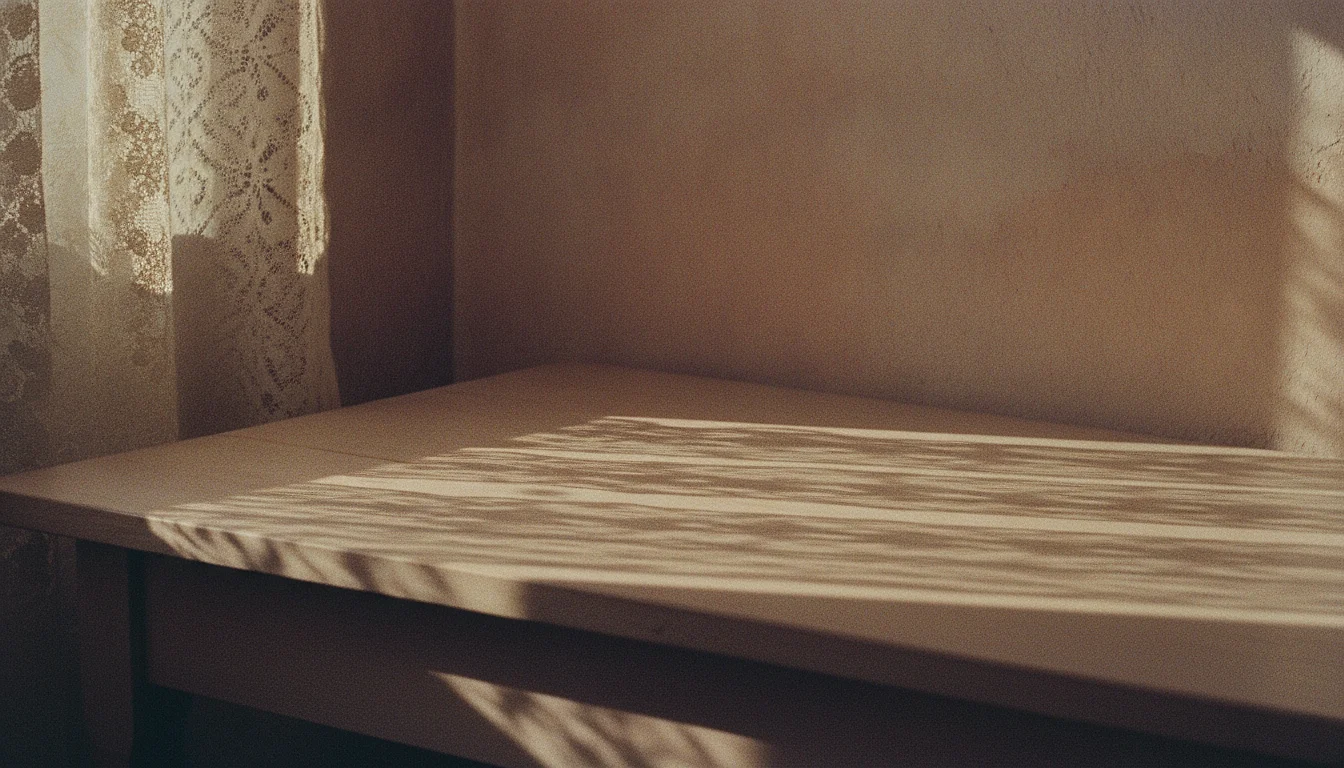 Afternoon sun through a lace curtain throwing a precise symmetrical pattern of light across a plain kitchen table.